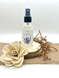Hand sanitizer bottle with spray pump and lavender label, clear liquid in glass
