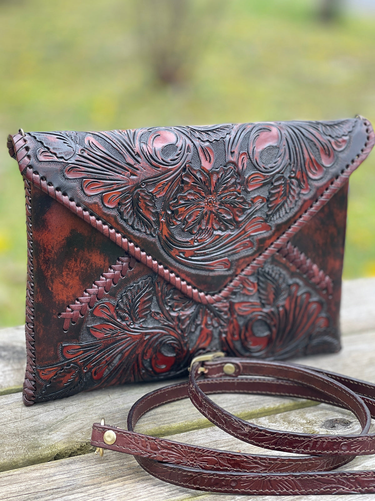 Hand-tooled leather crossbody clutch bag, dark brown with carved floral design and strap