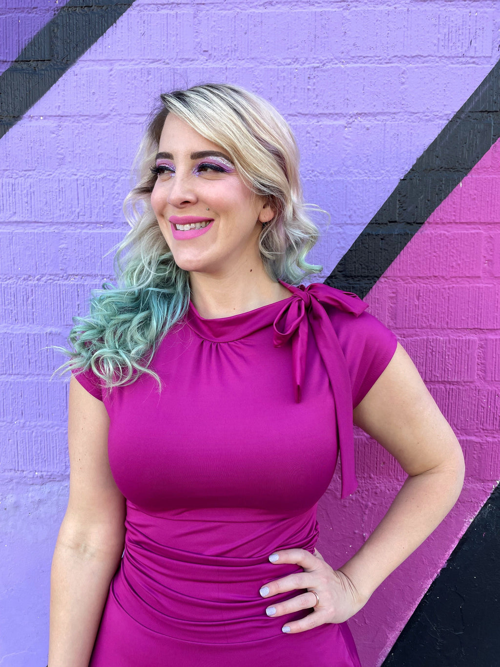 Magenta fitted midi dress close-up with ruched waist and bow-tied neckline