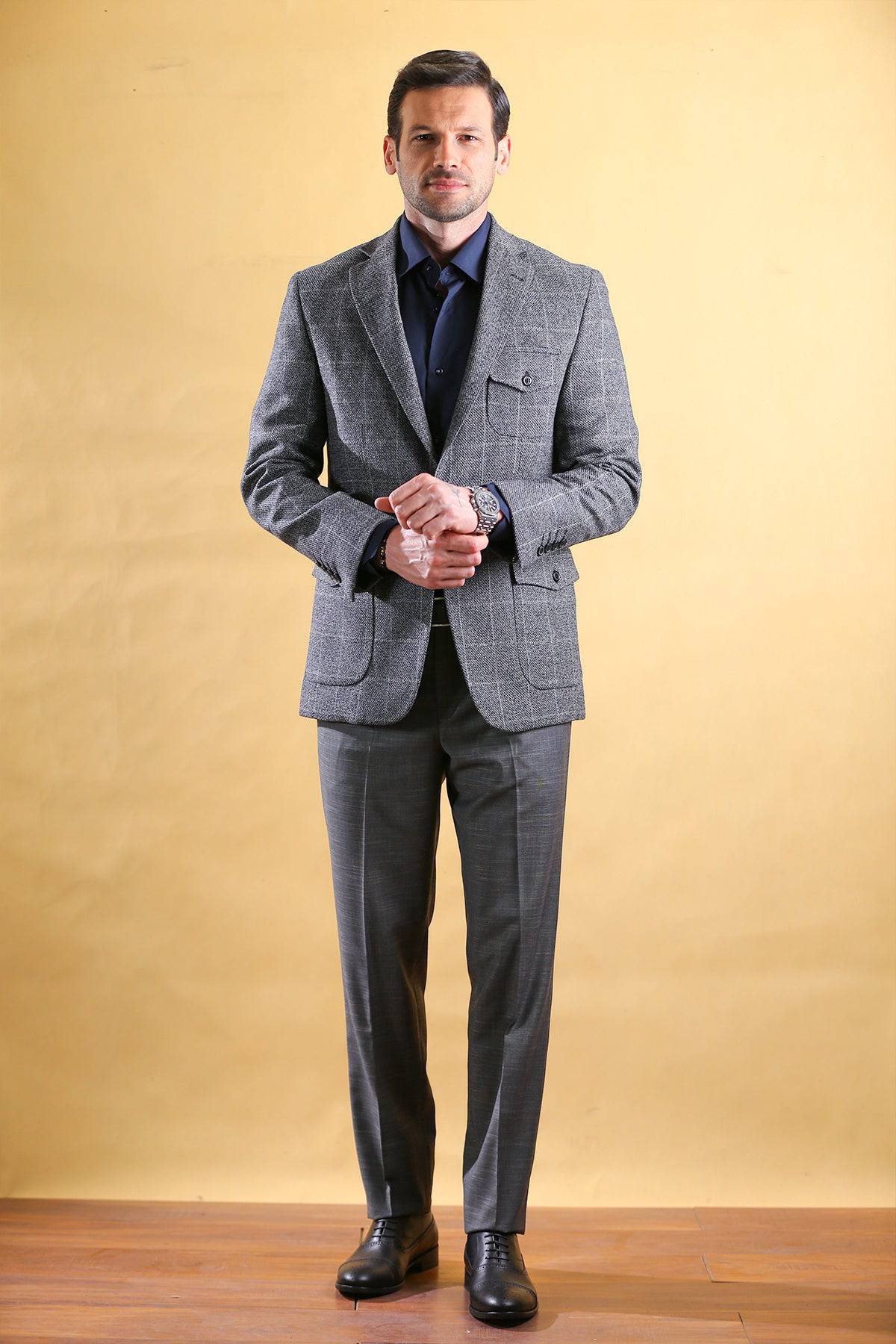 Gray tailored blazer with notch lapels and flap pockets worn with gray trousers