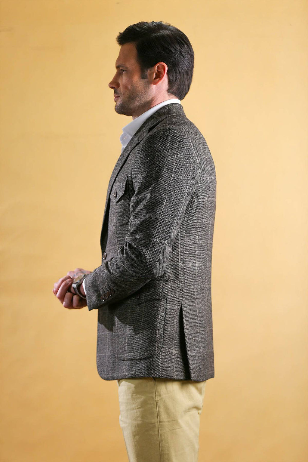 Men's vintage blazer in dark gray check texture, side profile with vented back hem.