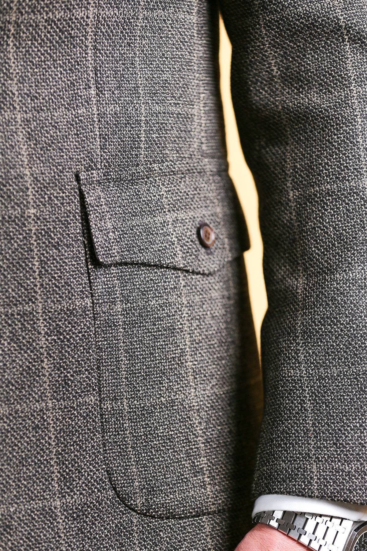 Men's vintage blazer pocket and seam detail in dark gray check texture, metal button.