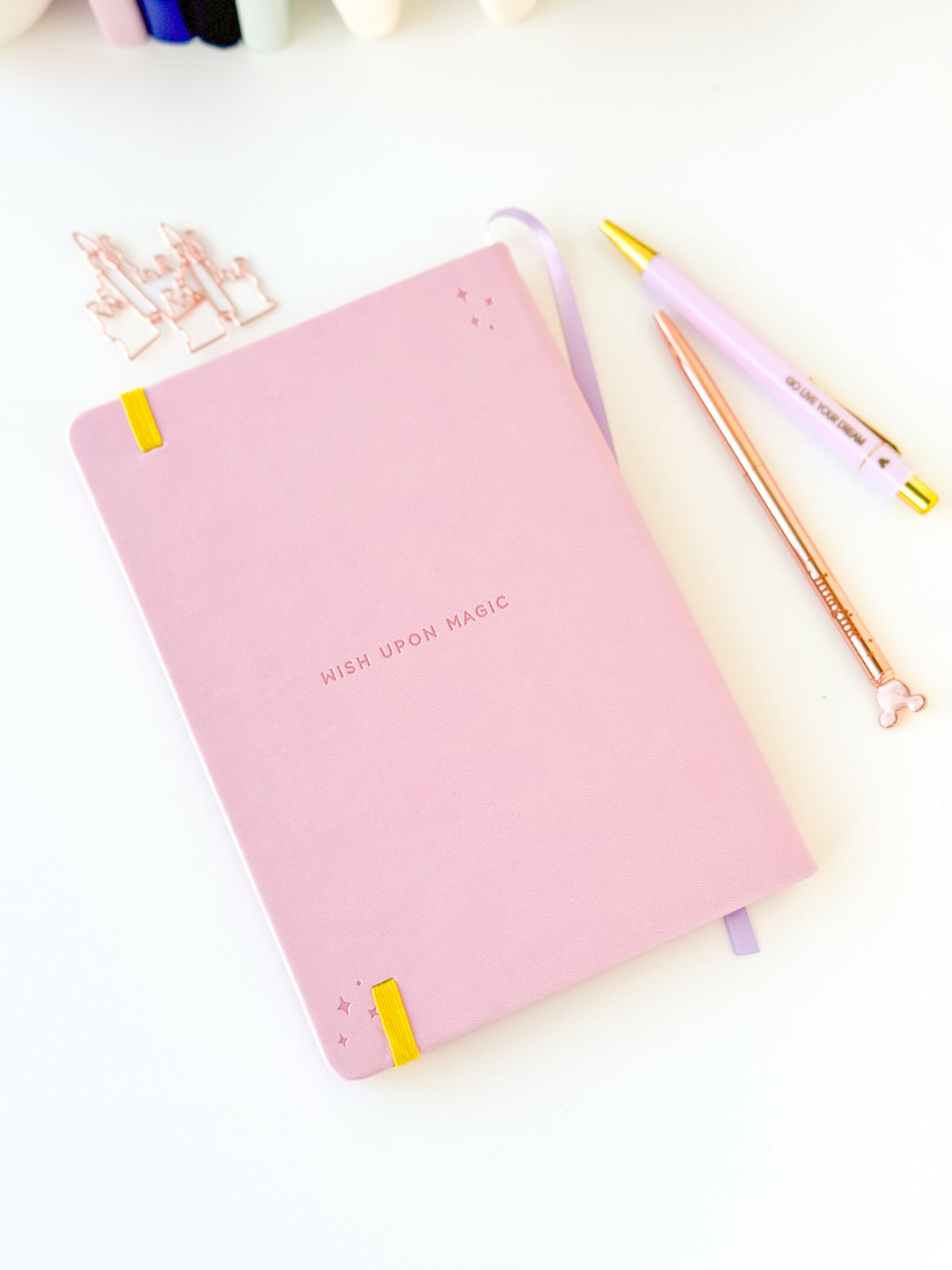 Pink notebook with embossed 'Wish upon magic' text and yellow corner rings