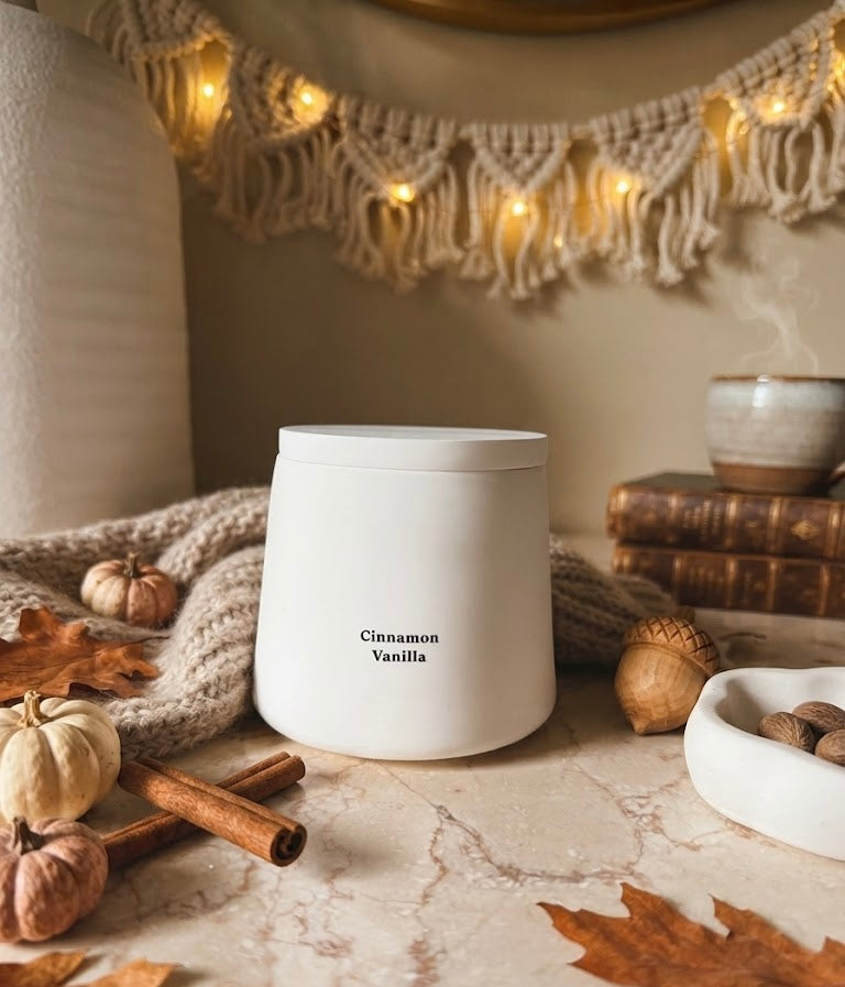 White cylindrical scented candle with flame, simple Cinnamon Vanilla label