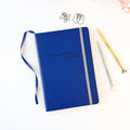 Blue embossed notebook with star pattern, ribbon bookmark, and white spine