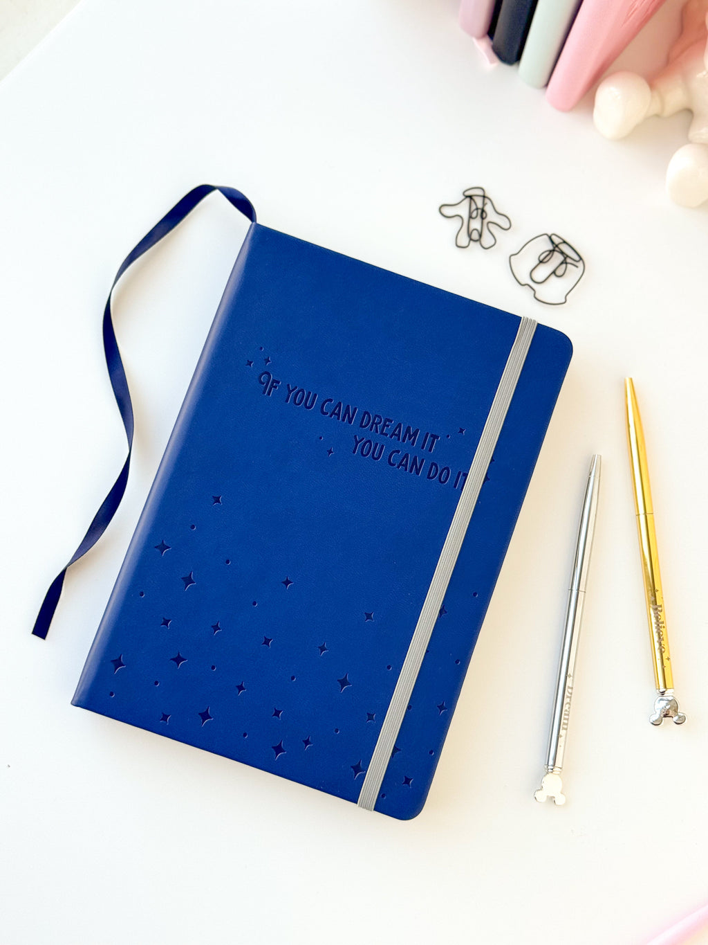 Blue embossed notebook with inspirational quote, ribbon bookmark, and gold pens