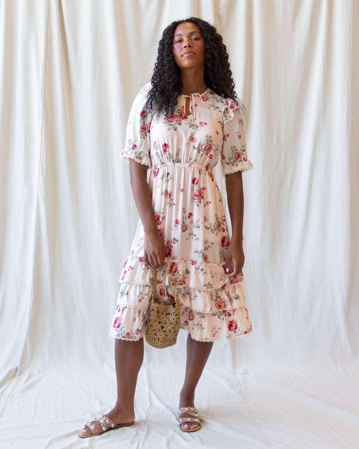 Cream floral tiered mini dress with short puff sleeves, lace trim, and gathered ruffle hem