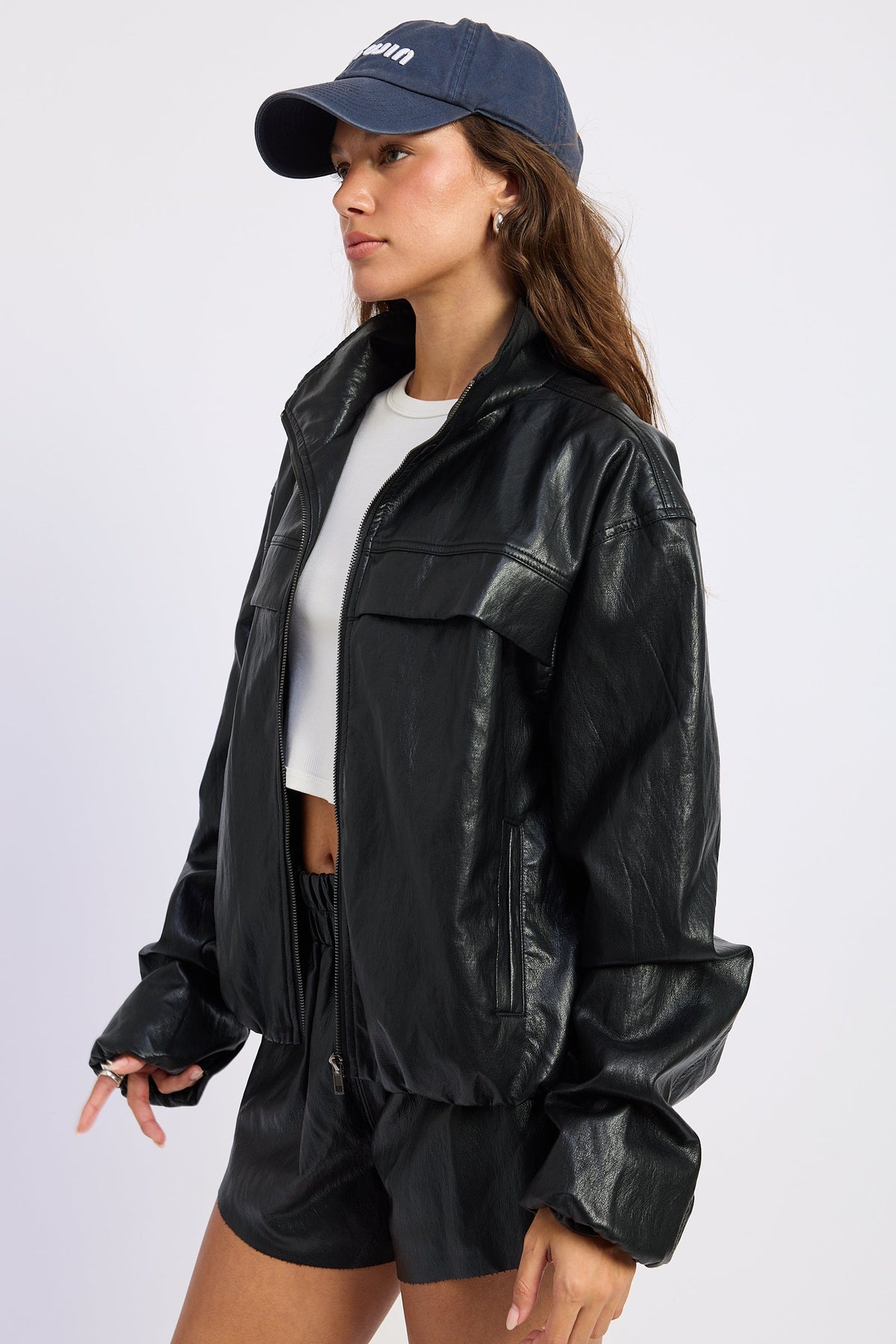 Black leather-look jacket with flap pockets and long sleeves, side profile