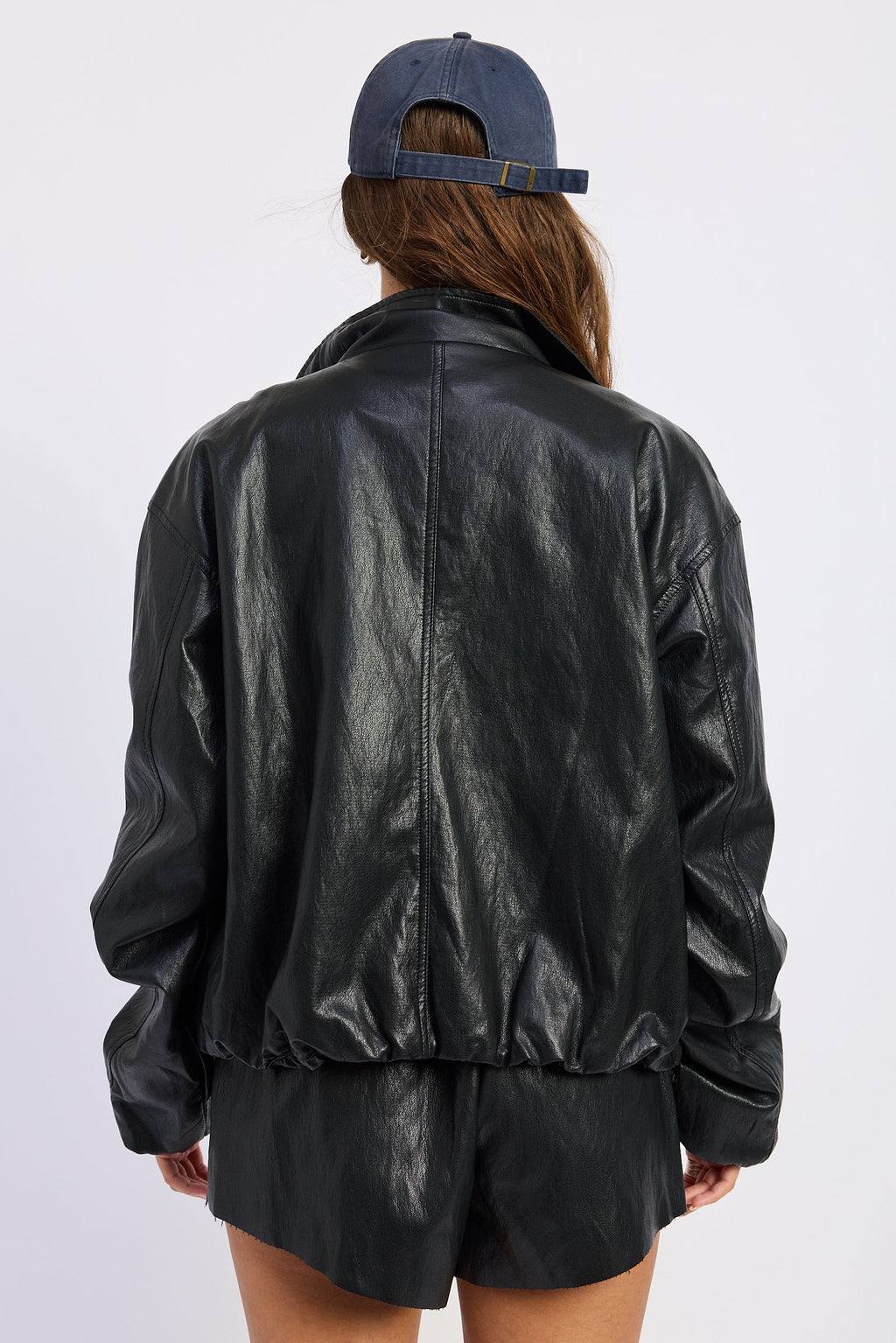 Back view of black leather-look jacket with button cuffs and gathered hem