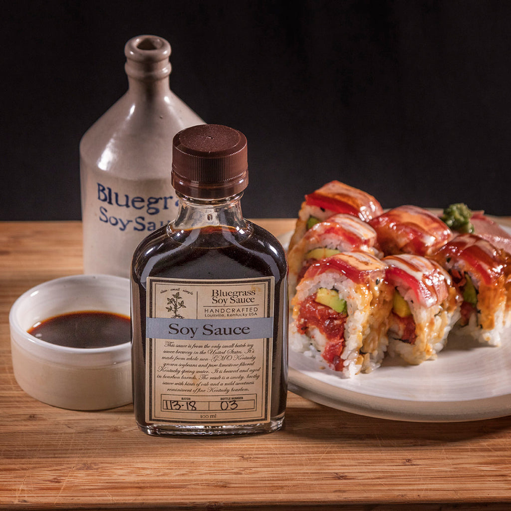 Soy sauce bottle with small cup and sushi rolls on plate