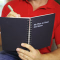 Spiral-bound black notebook open, showing lined pages and metal rings at spine