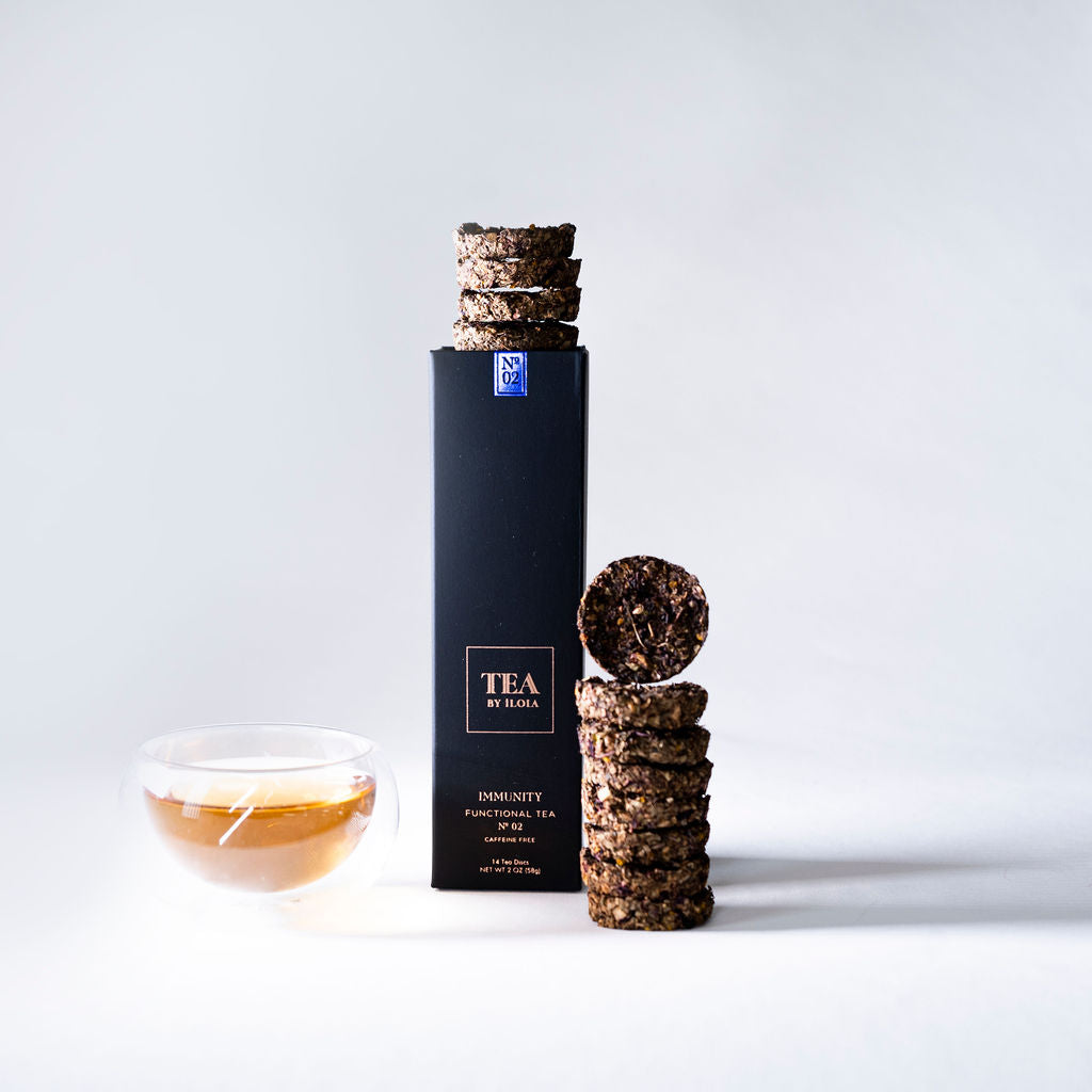 Immunity No. 02 herbal tea box with tea discs and a glass cup of brewed tea