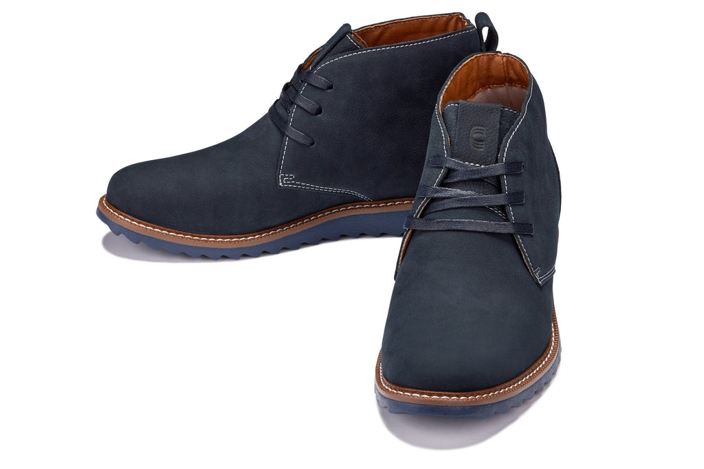 Dark blue nubuck chukka boots with lace-up closure, fold-over collar, and brown-edged sole