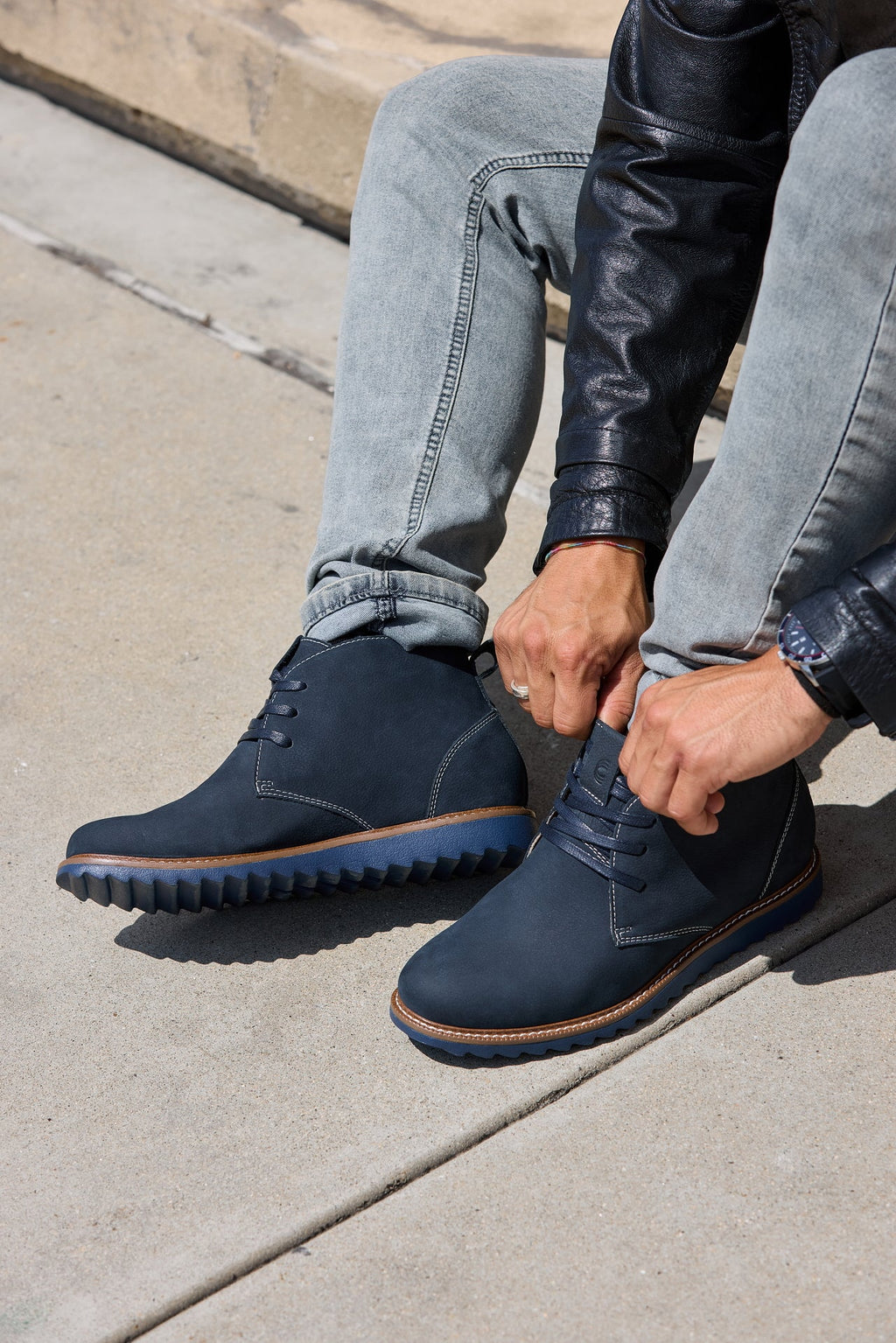 Close-up of navy nubuck chukka boots with lace-up eyelets and brown welt trim