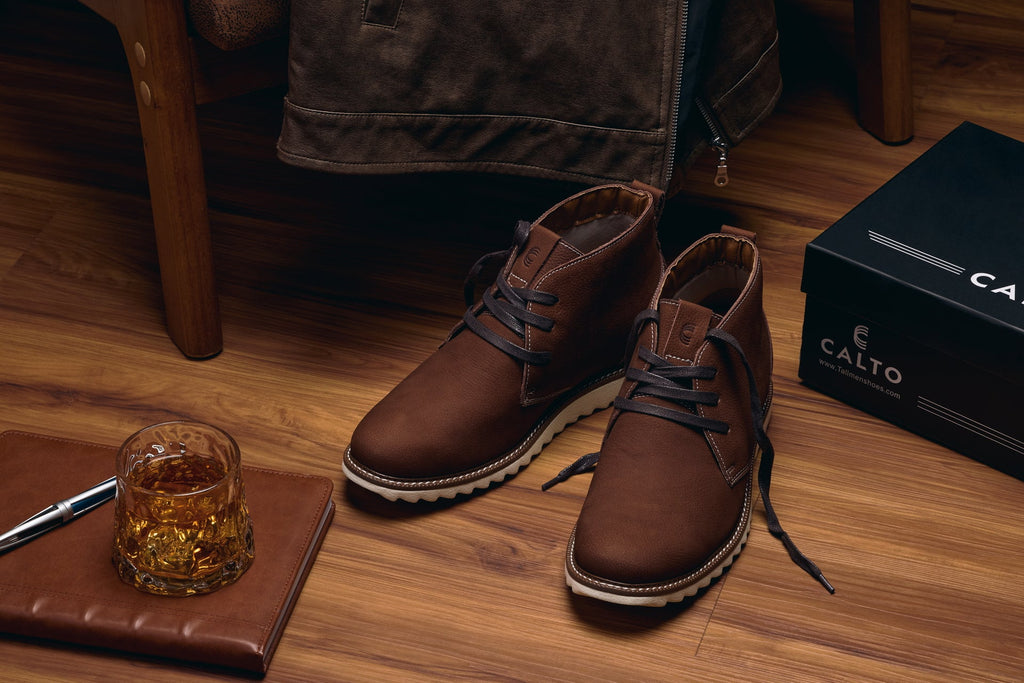 Brown nubuck chukka boots worn with pants; lace-up front and white rubber outsole