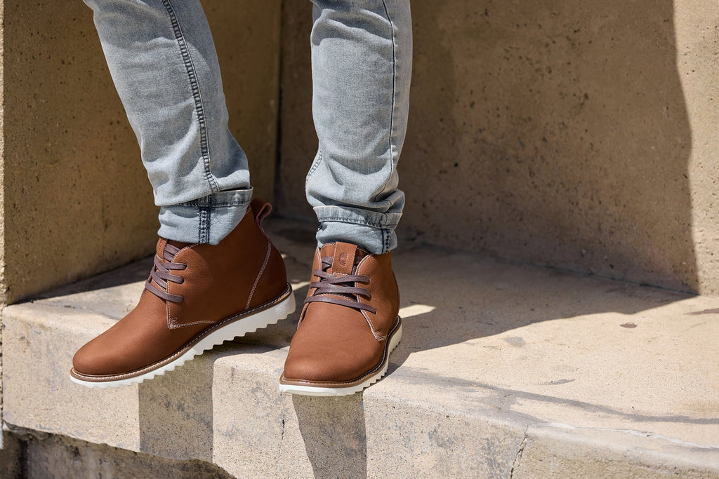 Brown nubuck chukka boots worn with light jeans; lace-up front and white outsole