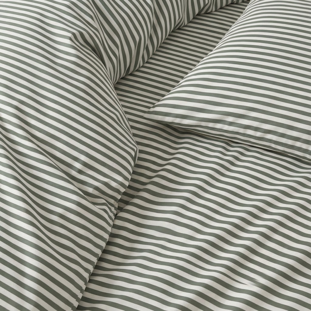 Close-up of striped sateen bedding fabric in white and muted green bands.