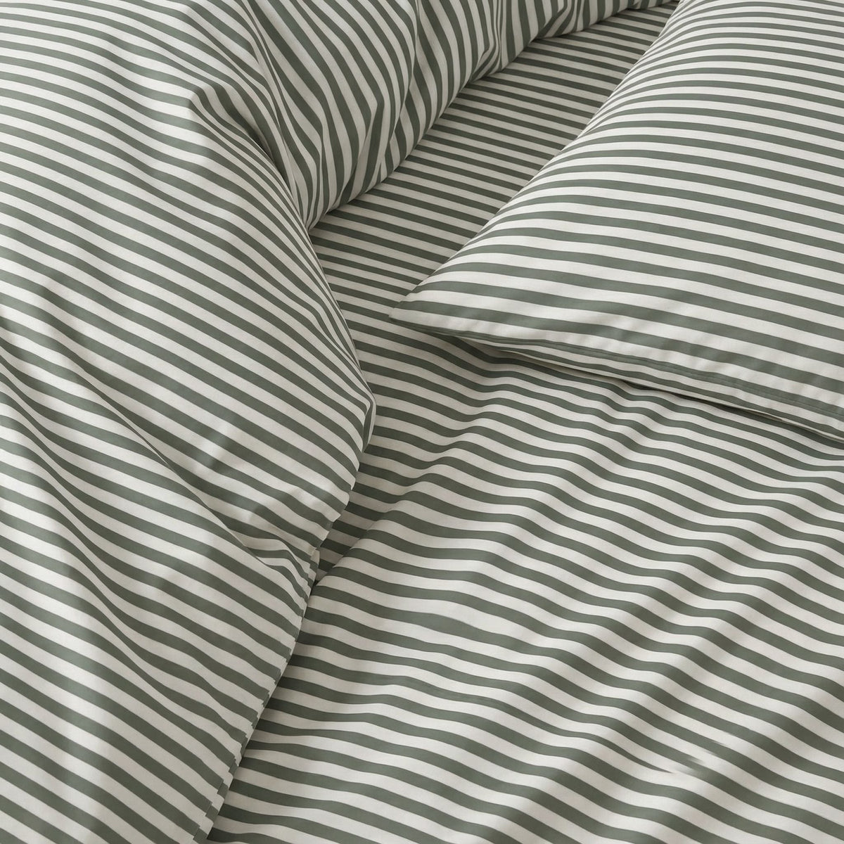Close-up of striped sateen bedding fabric in white and muted green bands.