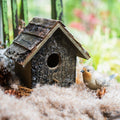 Weathered wood decorative bird house with round entrance hole and angled shingle roof