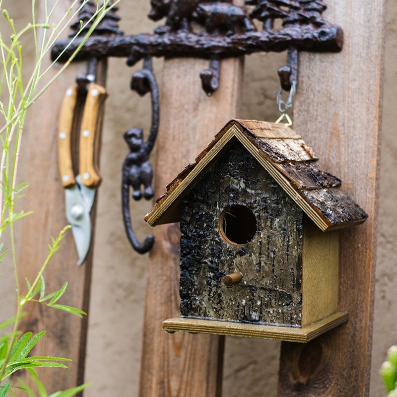 Hanging weathered wood bird house with circular entrance hole and side perch