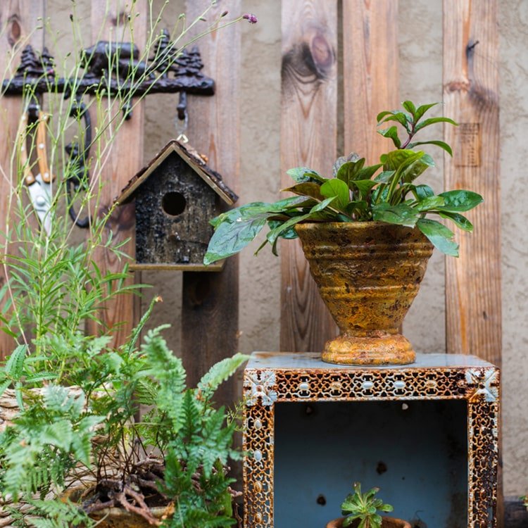 Weathered wood bird house with circular entrance hole and slatted shingle roof