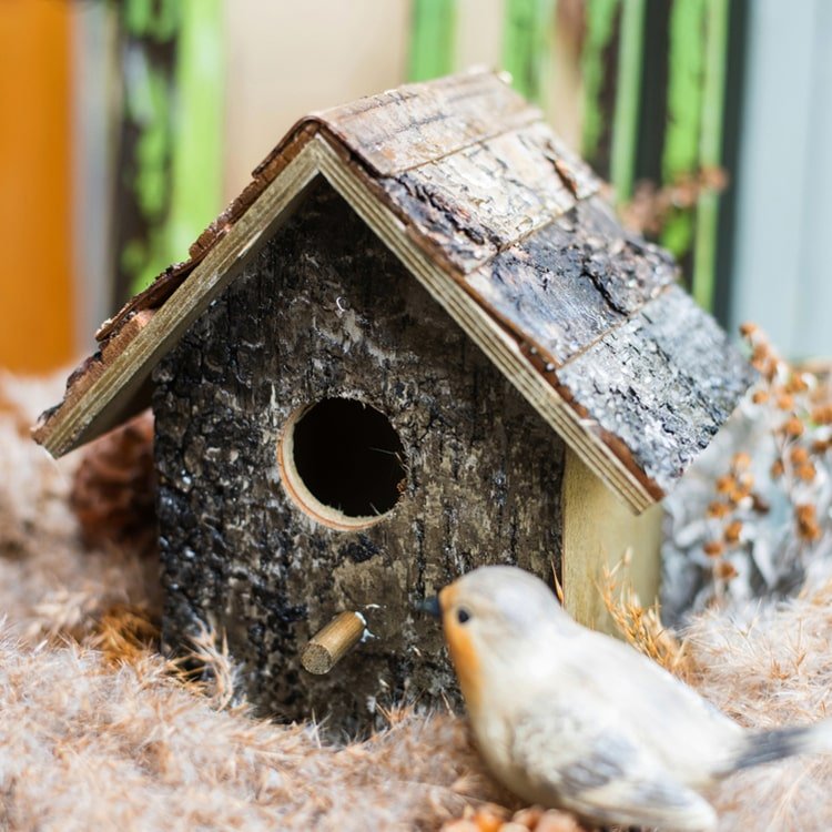 Weathered wood decorative bird house with round entrance hole and front perch