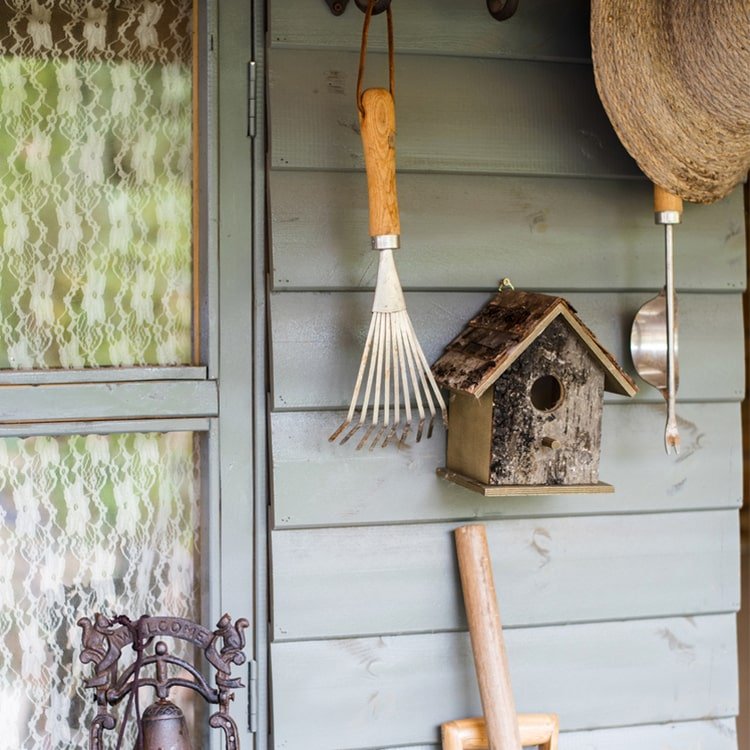 Weathered wood hanging bird house with round entrance hole and slanted shingle roof