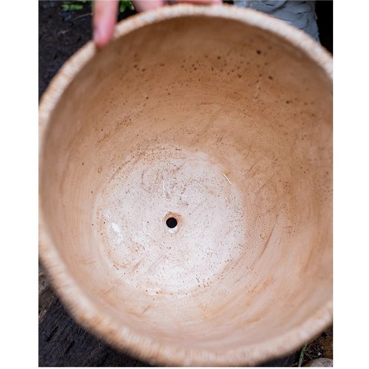 Concrete cement planter top view with woven rattan rim and drainage hole