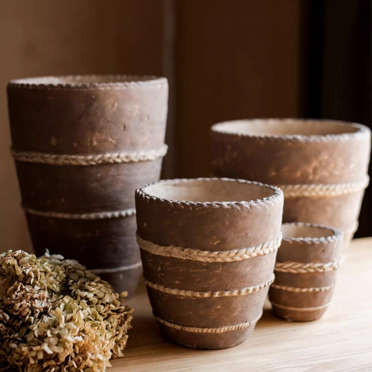 Stacked terracotta-toned planters with rope trim and textured banded sides