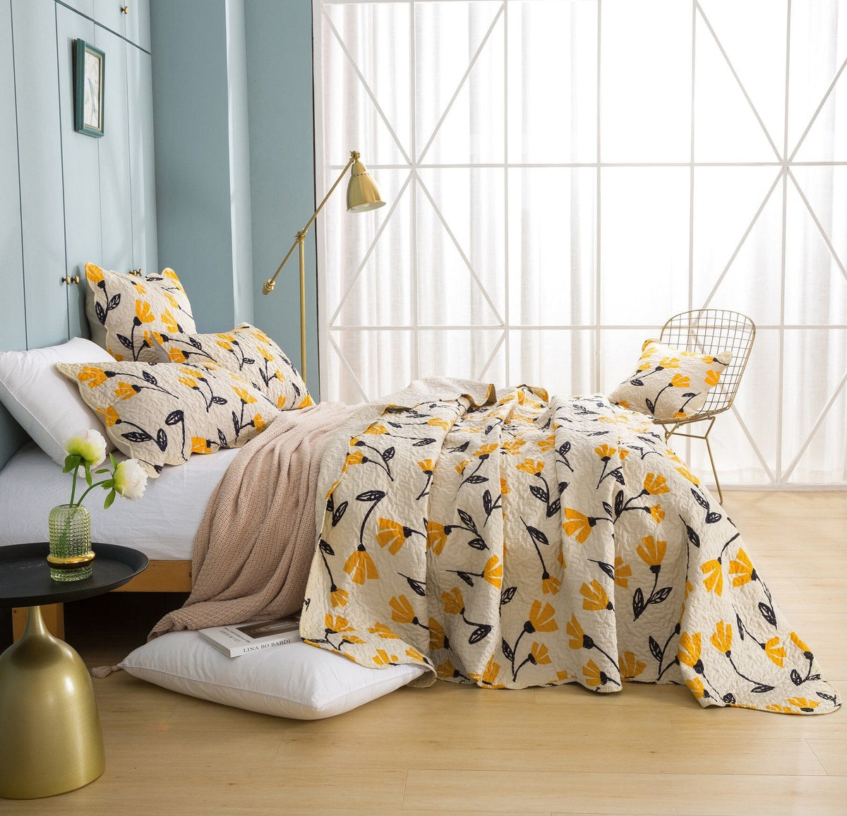 Botanical bedding on bed: ivory comforter with yellow flowers and dark leaves, plus pillows