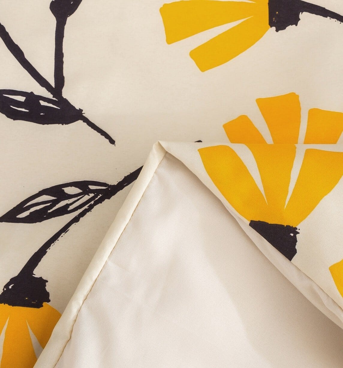Cream duvet cover close-up with yellow flower print and black leaf stems