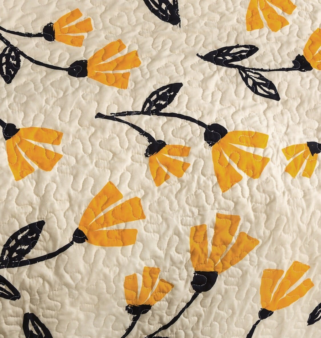 Ivory quilt with quilted texture, repeating yellow and black floral silhouettes
