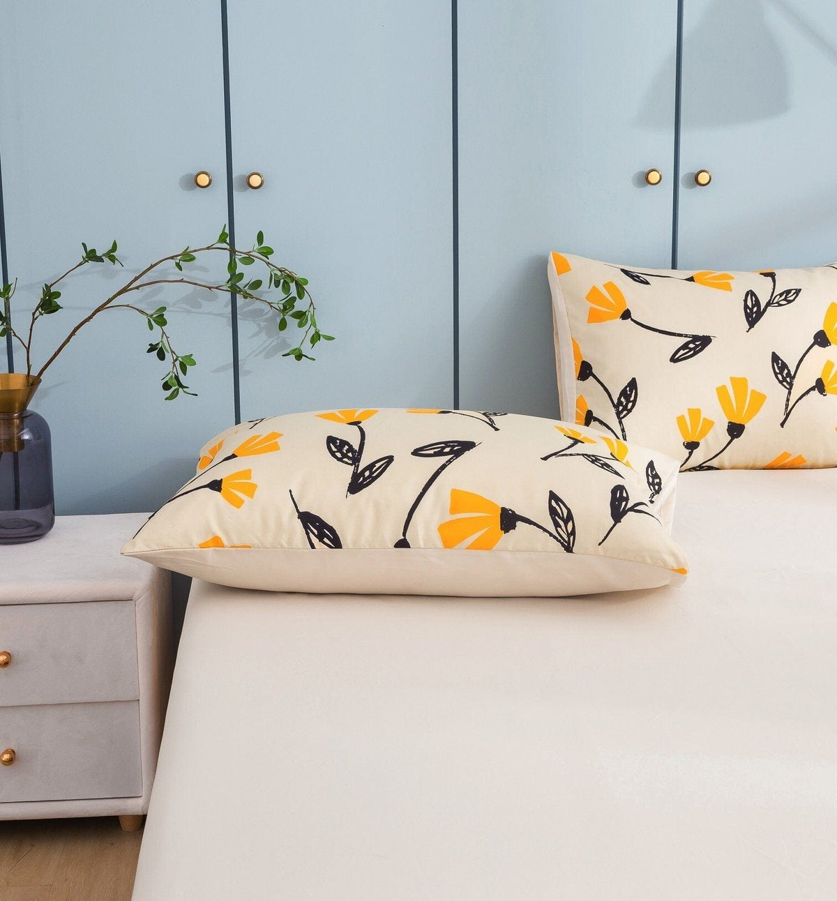 Close-up of ivory pillow with yellow flower and dark leaf pattern on bed