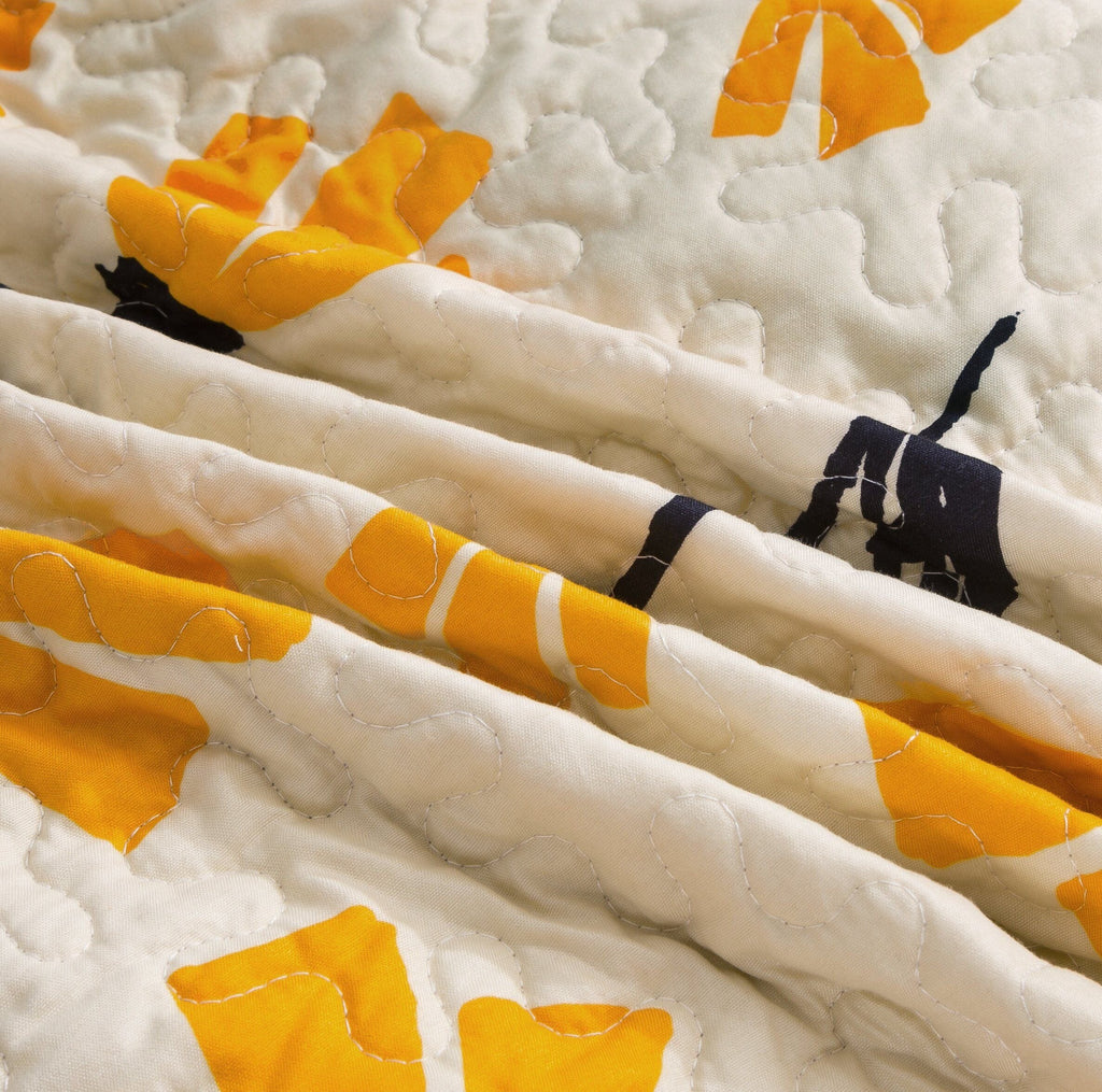 Ivory quilt border detail with yellow petal shapes and black stems, quilted stitching