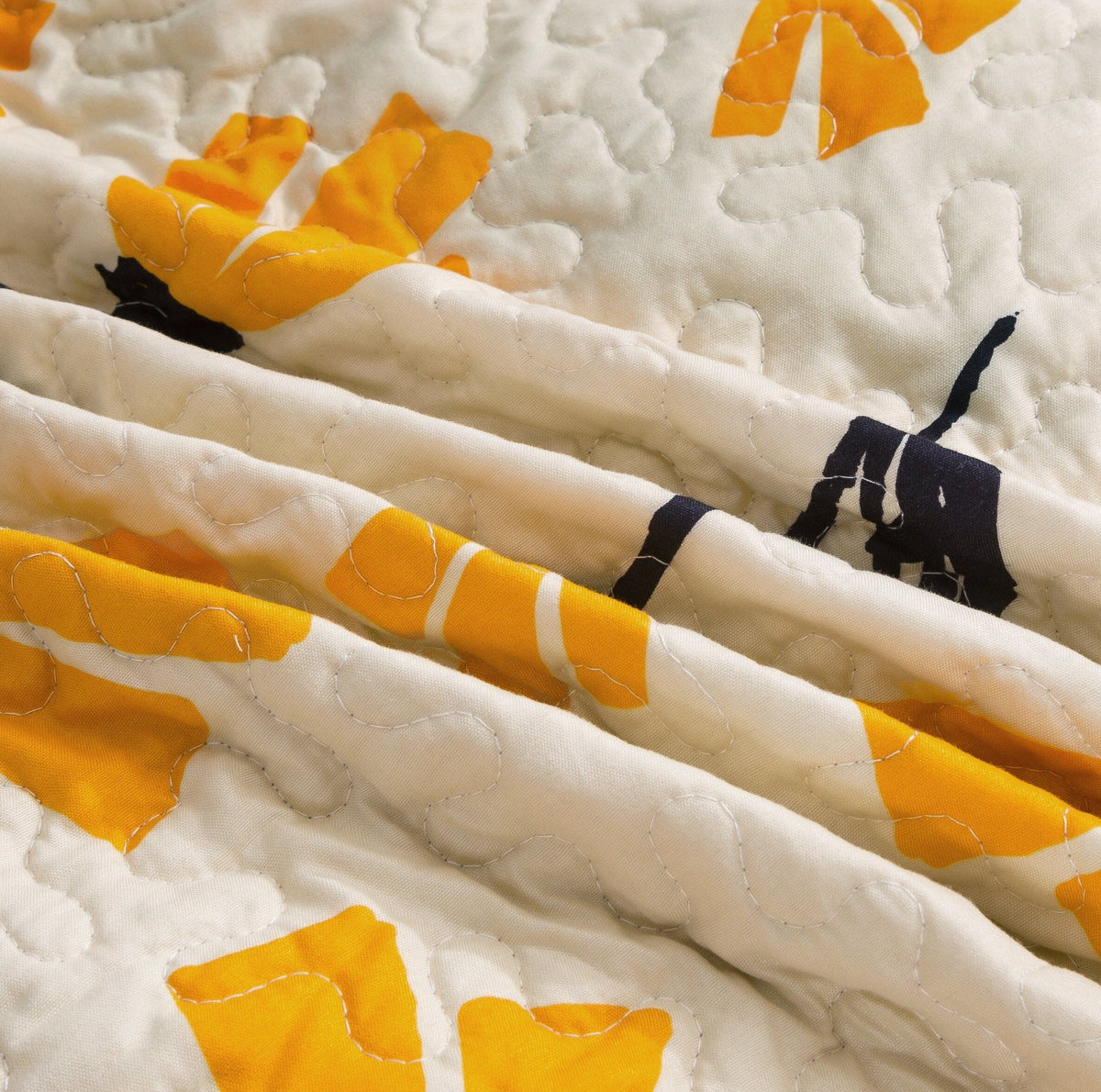 Ivory quilt border detail with yellow petal shapes and black stems, quilted stitching