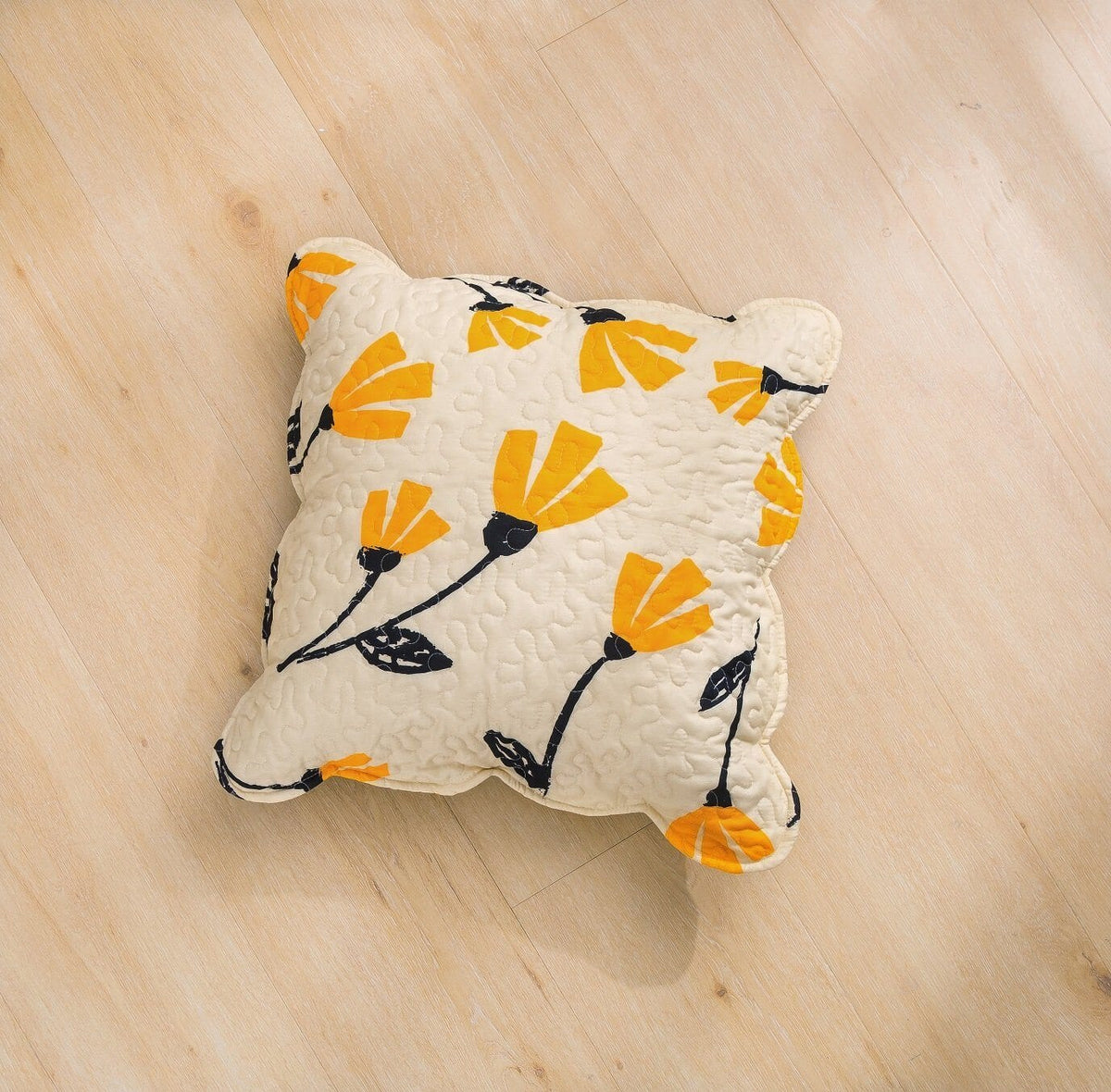 Quilted ivory accent pillow with yellow floral pattern and black vines, corner tassels
