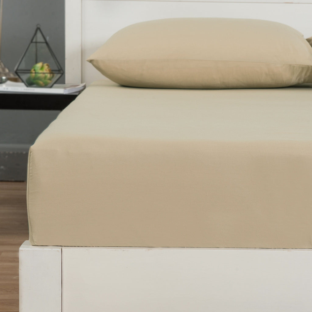 Light tan flat sheet folded on bed with neatly stitched fabric edge