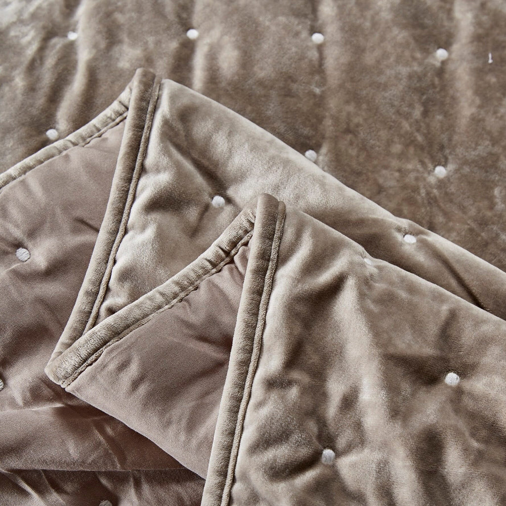 Taupe tufted velvet quilt corner with stitched trim and buttoned tufts, folded detail
