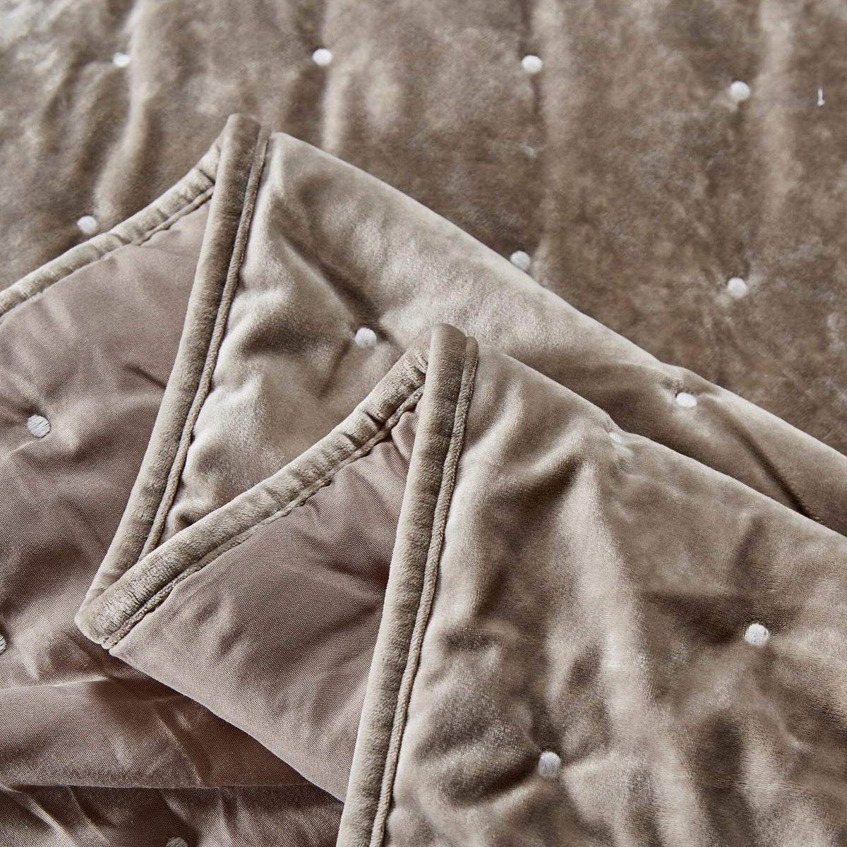 Taupe tufted velvet quilt corner with stitched trim and buttoned tufts, folded detail