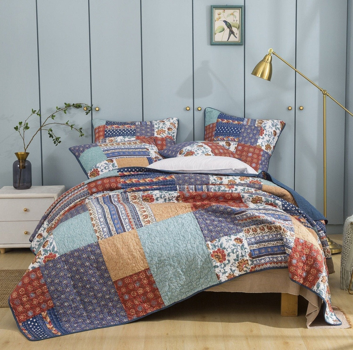 Quilted patchwork bedspread with blue, red, and cream floral and geometric blocks