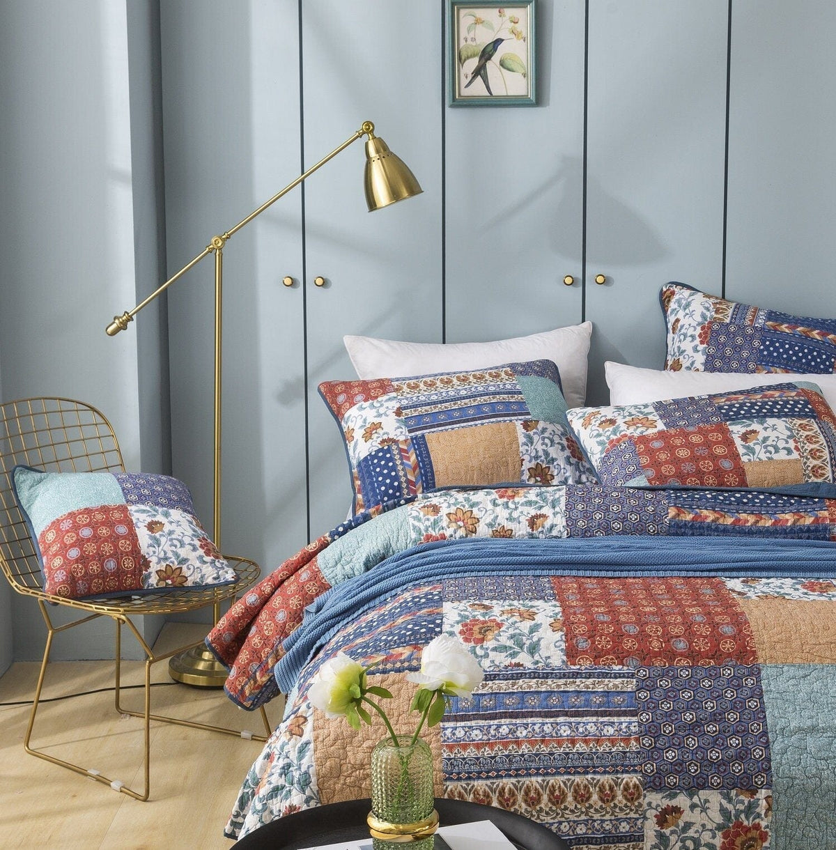 Patchwork quilted bedspread with blue, red, tan, and cream floral pattern