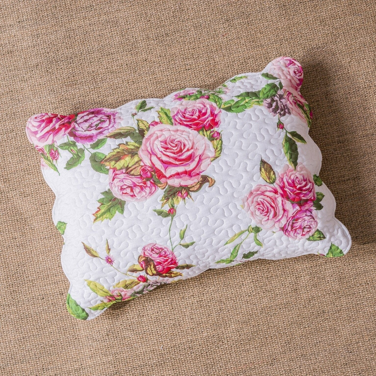 Pink rose floral decorative pillow with white backing and green leaves