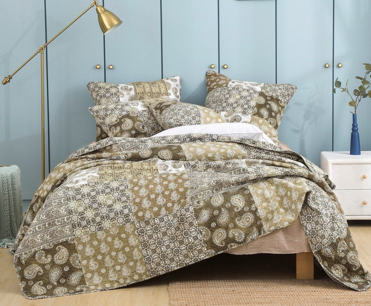 Olive-brown paisley bedding set on bed with layered patchwork comforter and pillow shams
