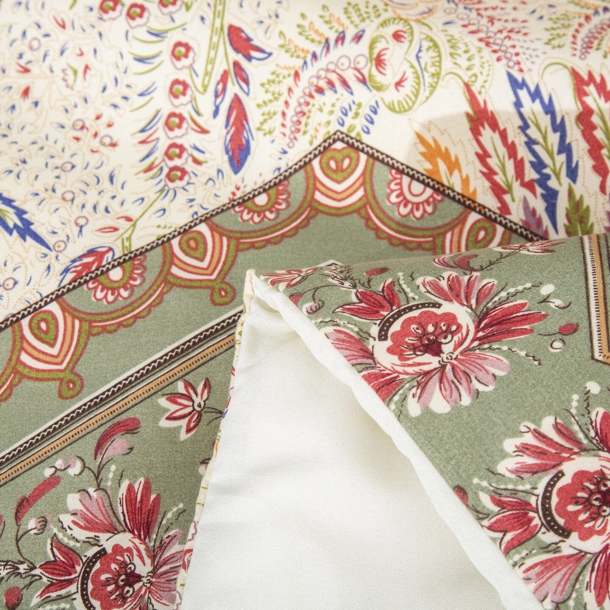 Floral pillow cover detail with red flowers on sage and beige patterned fabric