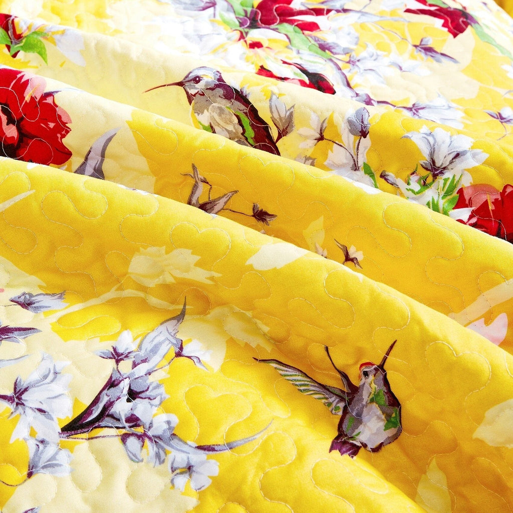 Close-up of yellow quilted fabric with colorful bird-and-flower floral print