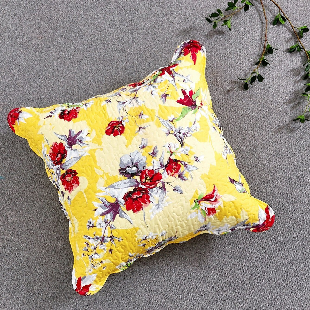 Quilted yellow floral pillow with bird and flower print, red and blue accents