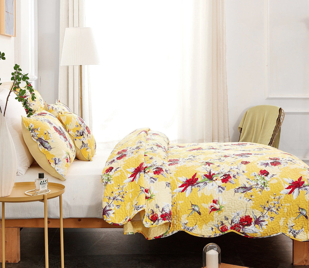 Yellow floral quilt and pillow sham set with hummingbird print on bed