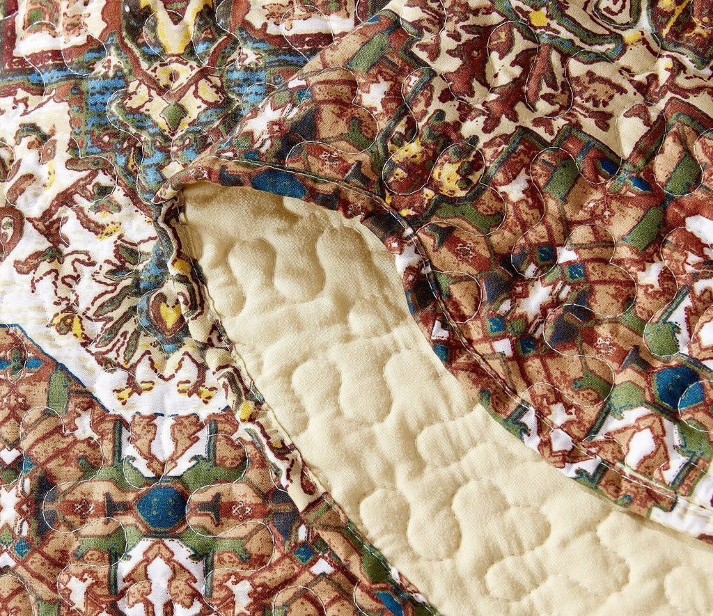 Close-up view of quilted bedspread texture with cream backing and medallion print