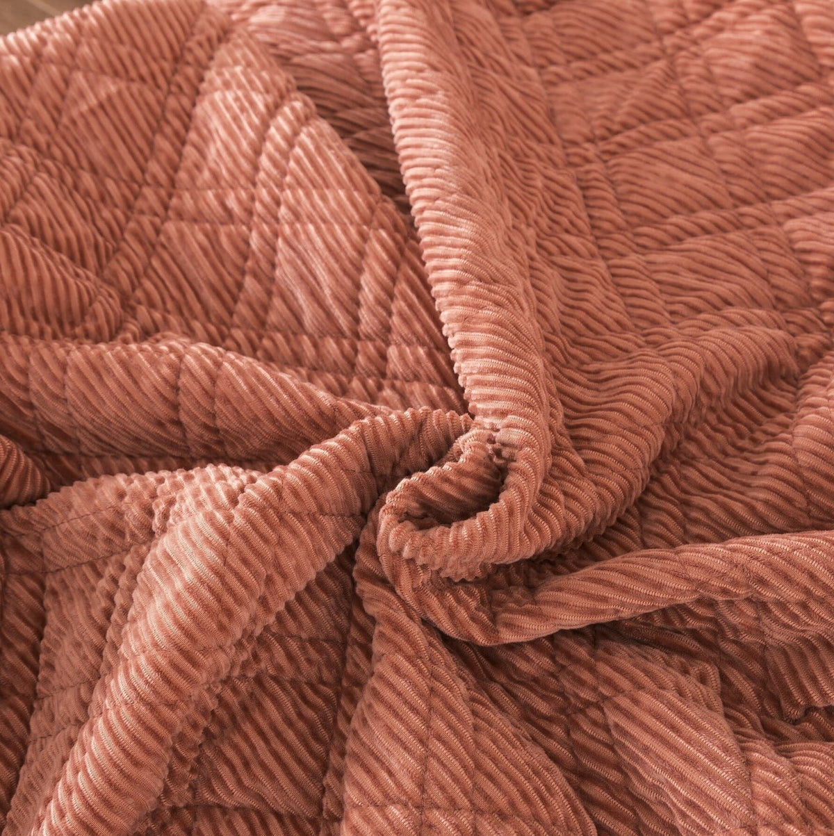 Close-up terracotta coral velour corduroy with crisscross quilted ridges