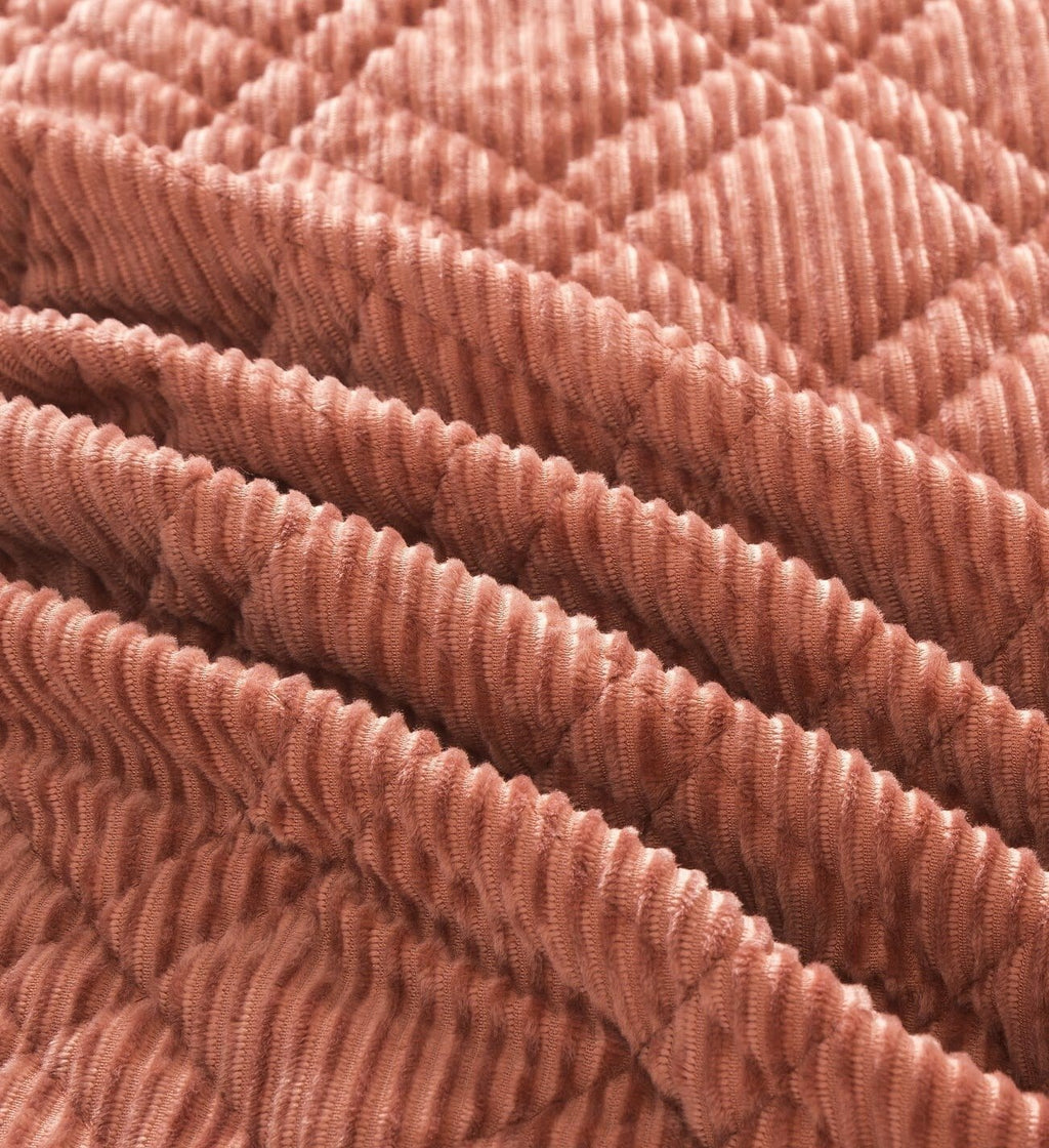 Close-up of terracotta coral velour corduroy fabric with ribbed texture